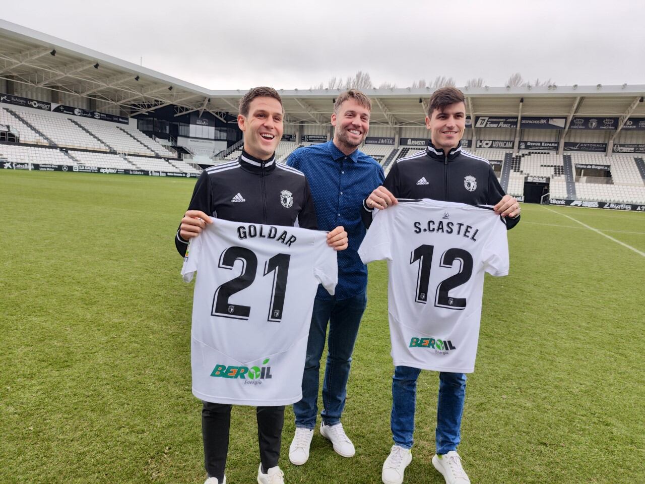 David Goldar y Sergio Castel posan con sus camisetas del Burgos CF sobre el terreno de juego de El Plantío. Junto a ellos, Miguel Pérez 'Michu', director deportivo del club blanquinegro. / Foto: Radio Castilla