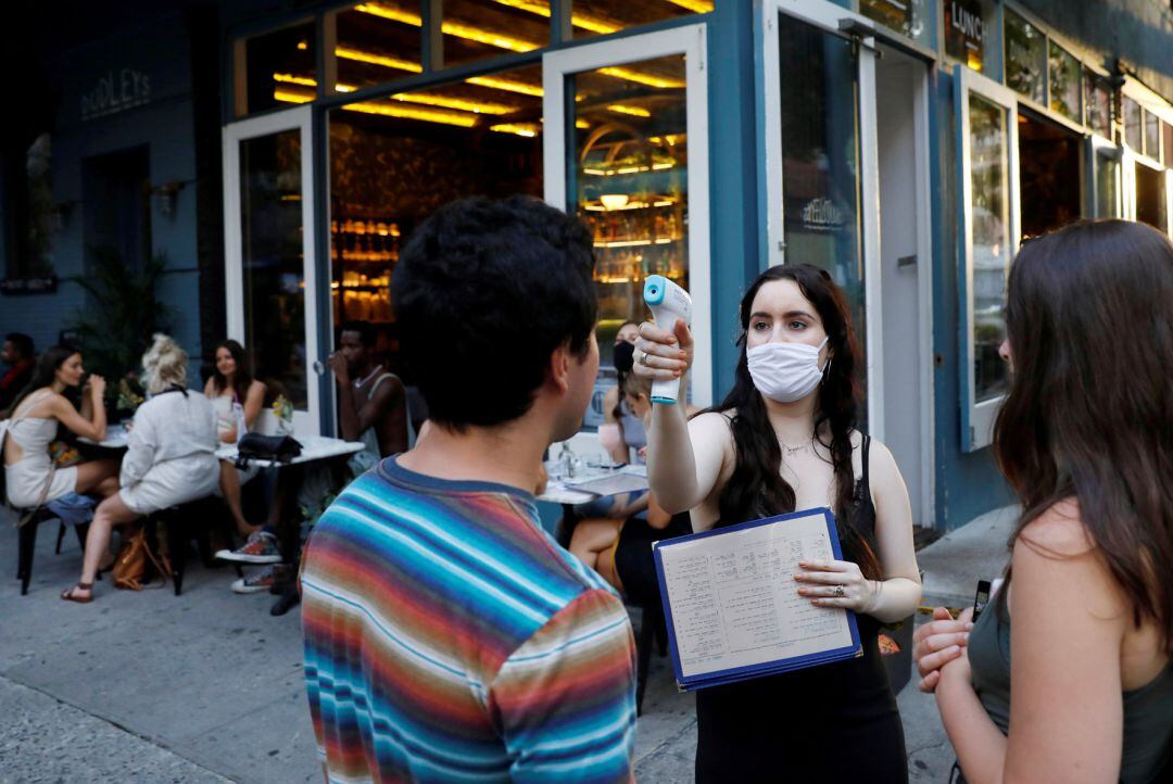 Una camarera toma la temperatura a un cliente en Nueva York.