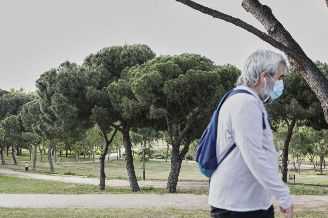 Un hombre con mascarilla pasea protegido por el parque de San Isidro, uno de los parques abiertos en la capital para evitar las aglomeraciones durante la desescalada ante el Covid-19