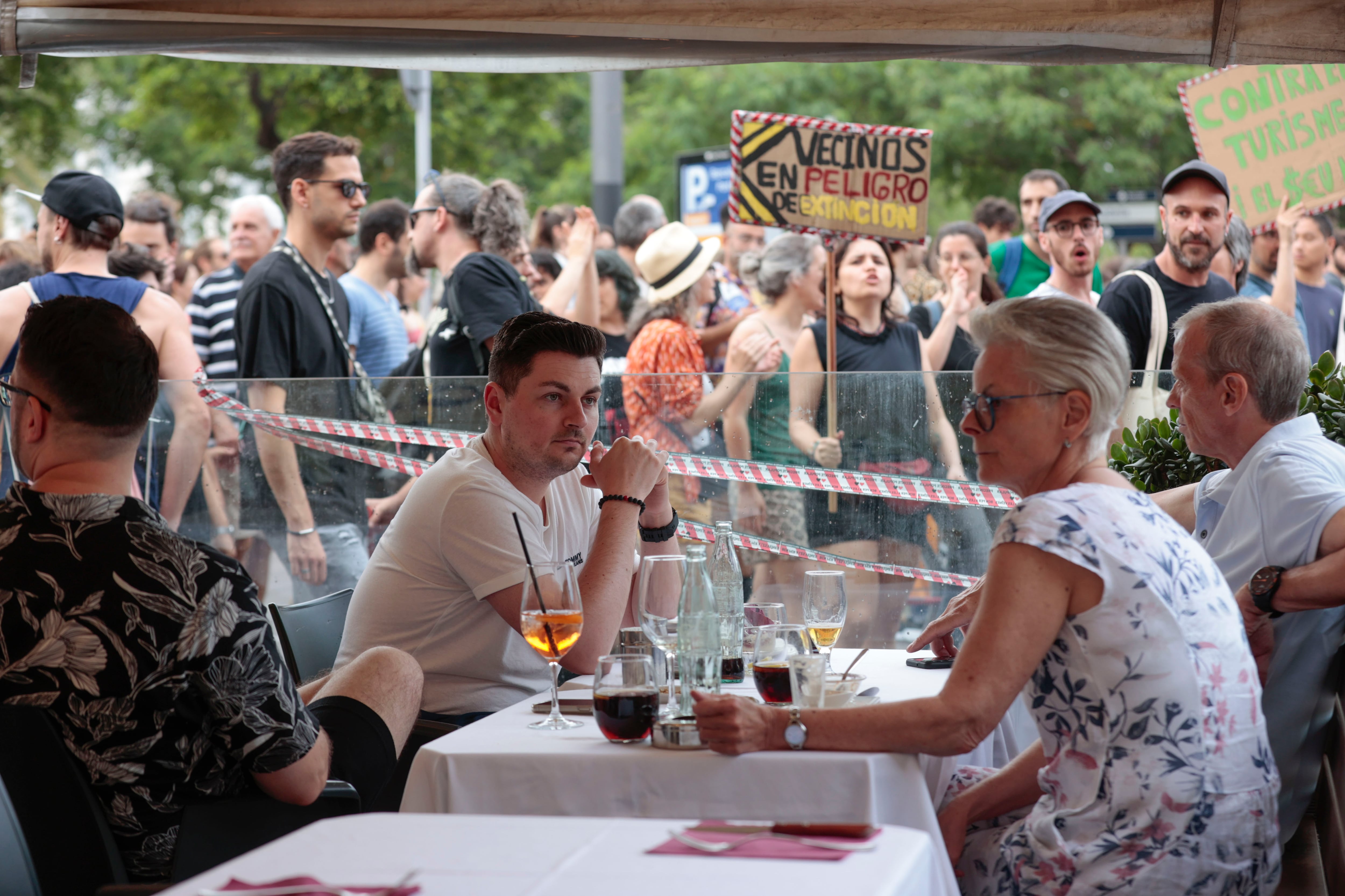 Varios turistas sentados en la terraza de un bar ante el paso de la manifestación.