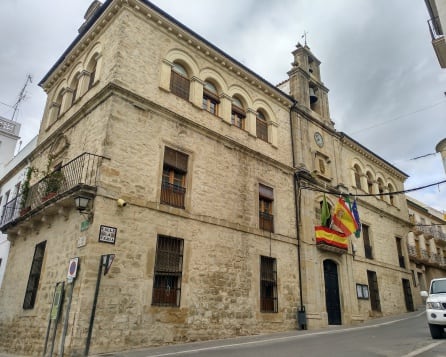 Fachada del ayuntamiento de Villacarrillo con dos banderas nacionales en el balcón principal, correspondiente a la alcaldía.