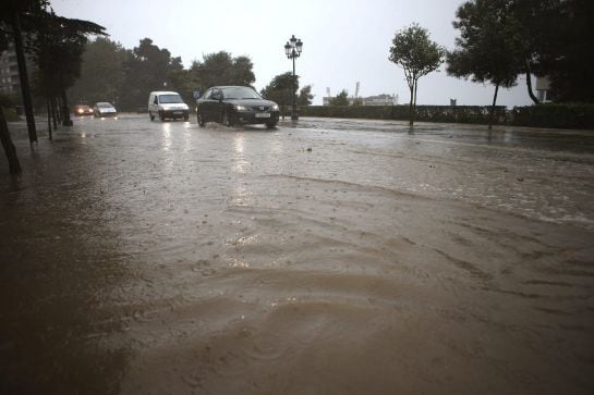 Varios coches circulan por una calle inundada en la falda del Monte del Castro, cerca del Ayuntamiento de Vigo