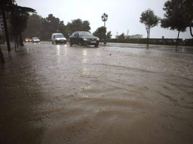 Varios coches circulan por una calle inundada en la falda del Monte del Castro, cerca del Ayuntamiento de Vigo