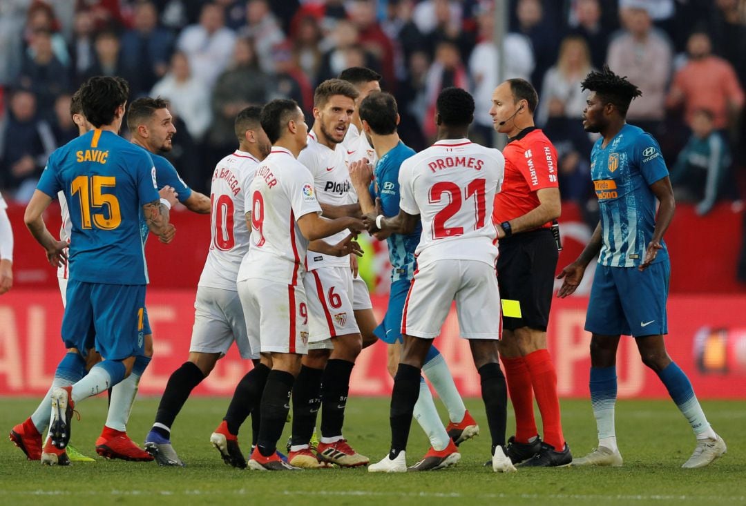 Referee Antonio Mateu Lahoz drops the yellow card as Sevilla&#039;s Quincy Promes holds back Atletico Madrid&#039;s Juanfran from Sevilla&#039;s Daniel Carrico