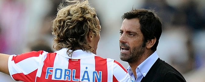 Forlán escucha a Quique durante un partido del Atlético