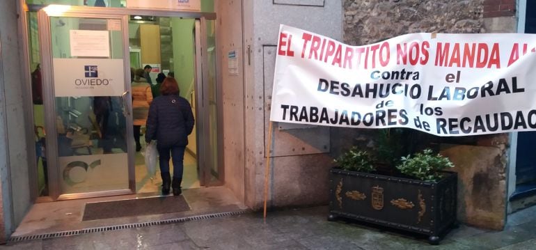 Entrada de la Oficina Municipal de Recaudación con una pancarta de protesta de los trabajadores de la actual concesionaria del servicio La Auxiliar de Recaudación.