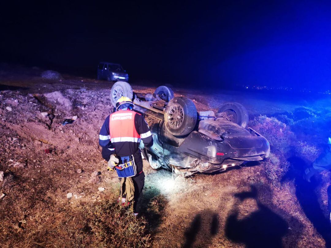 Un bombero del Consorcio de Seguridad y Emergencias de Lanzarote junto al vehículo volcado.