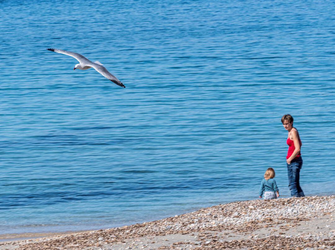 Una niña, junto a su madre en la playa