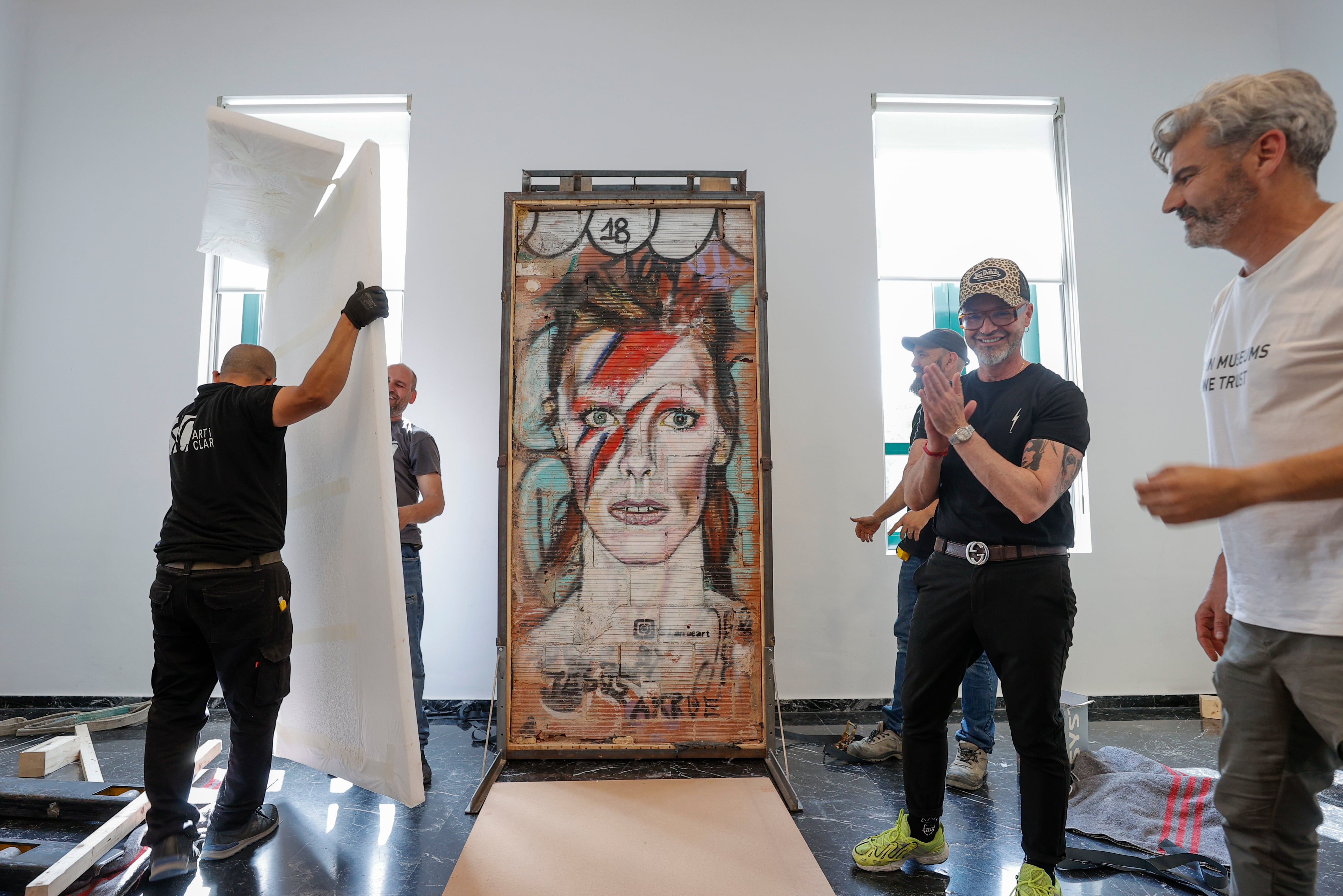 El artista Jesús Arrúe (2º d), asiste a la instalación del grafiti de David Bowie, obra procedente del Centre del Carme Cultura Contemporània, en la exposición permanente del LETNO, Museu Valencià dEtnologia.