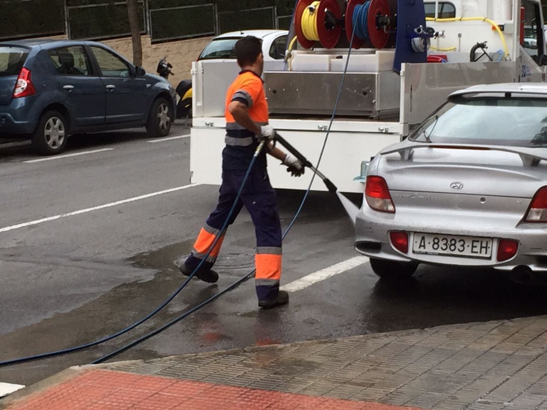 Un trabajador de la contrata de limpieza baldeando una calle de la ciudad