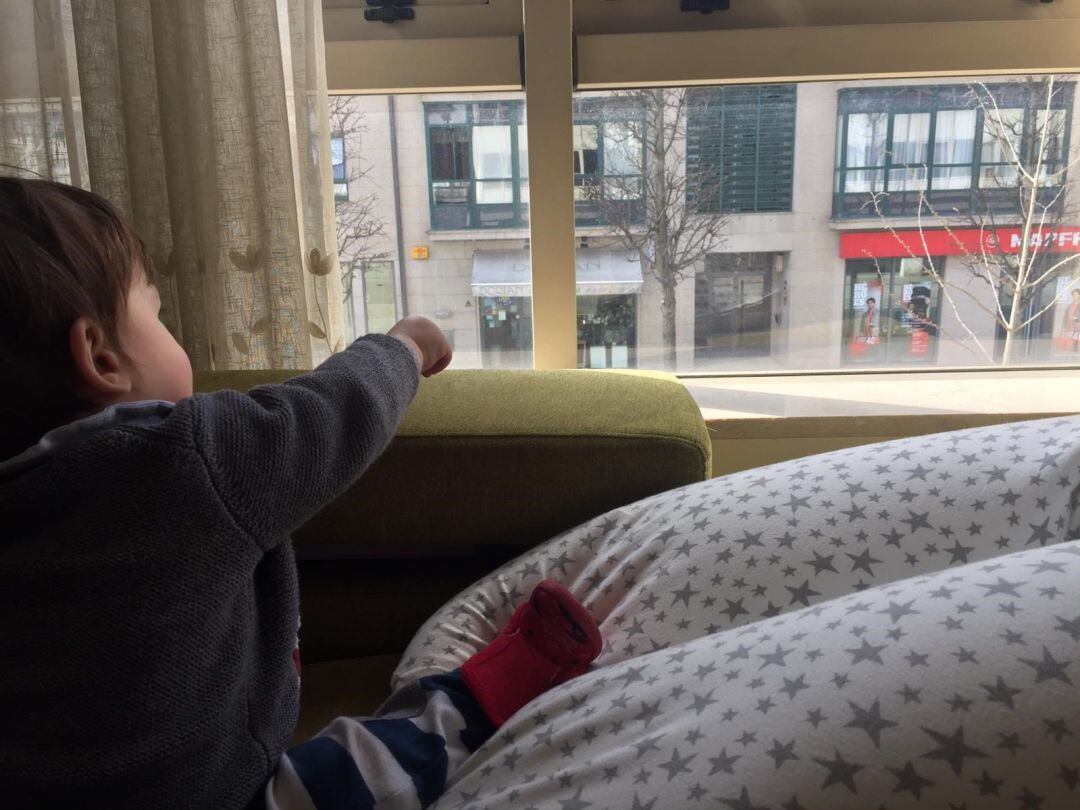 Un niño en el interior de un piso en Santiago mientras señala a la calle durante el confinamiento 