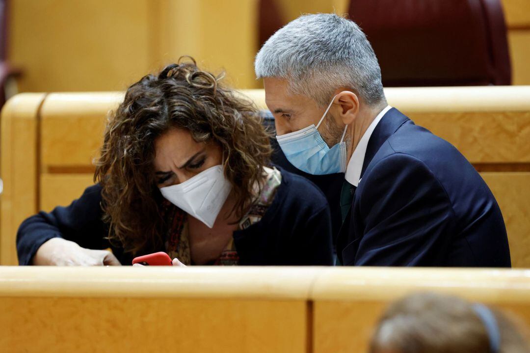 La ministra de Hacienda, María Jesús Montero, conversa con el titular de Interior, Fernando Grande-Marlaska durante la sesión de control al Gobierno que celebra este martes el pleno del Senado