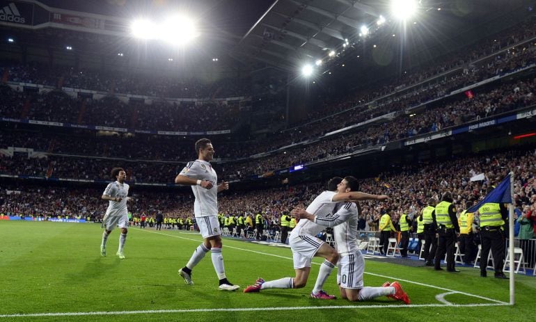 Real Madrid's Colombian midfielder James Rodriguez (R) is congratulated by his teammates during the Spanish league football match Real Madrid CF vs Malaga FC at the Santiago Bernabeu stadium in Madrid on April 18, 2015.   AFP PHOTO/ GERARD JULIEN
