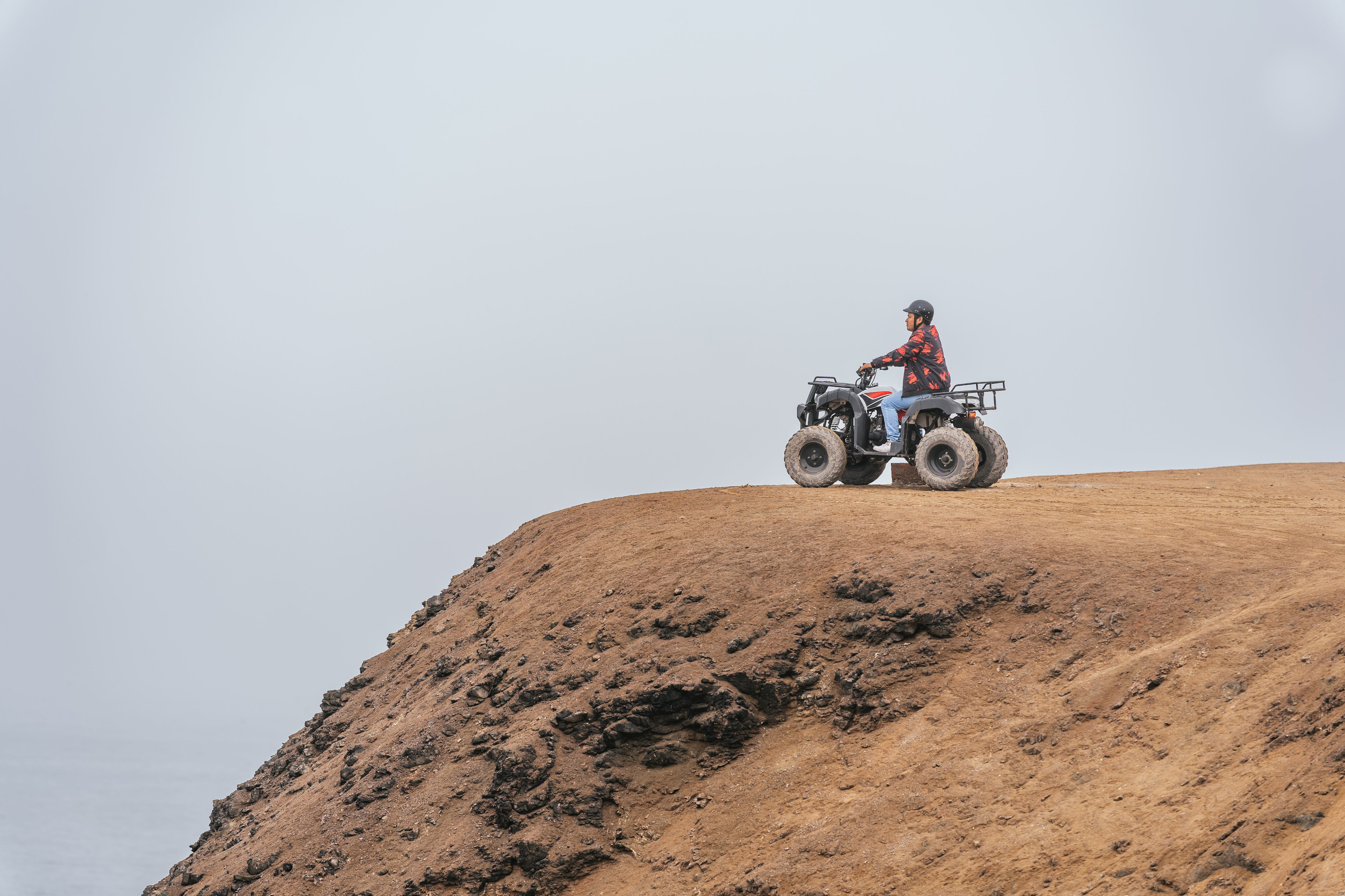 Person driving a quad bike over a sandy desert hill overlooking the landscape