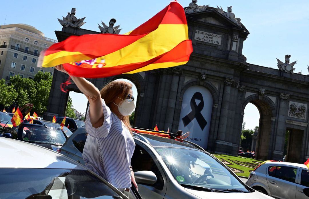 Una mujer levanta una bandera de España desde un coche en la manifestación promovida por Vox en Madrid contra la gestión del Gobierno en la pandemia del coronavirus.