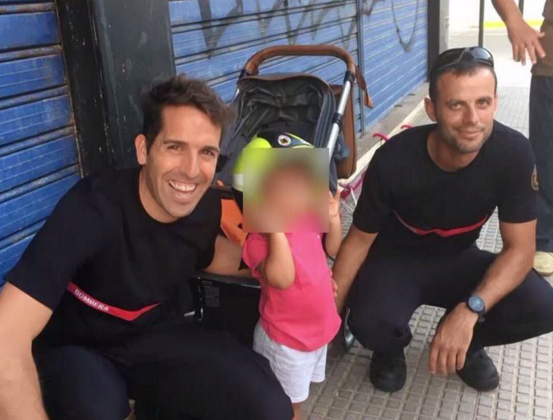 La niña de dos años junto a sus rescatadores que le han regalado un casco especial.  