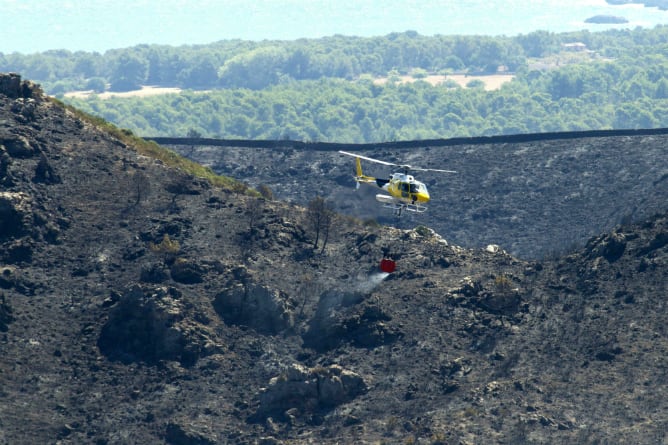 Un helicóptero sobre la superficie quemada por el incendio iniciado en Artà y Capdepera, en Mallorca, que ha afectado a más de 450 hectáreas, se encuentra estabilizado en un 75 por ciento