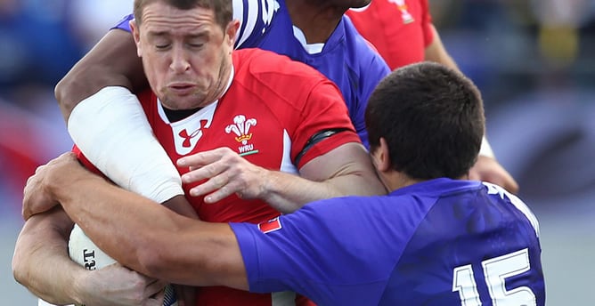 El pequeño Shane Williams disputa un balón contra dos jugadores de Samoa