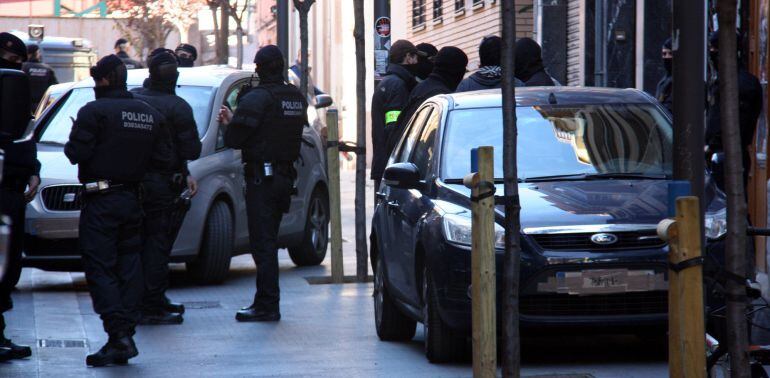 Els agents dels Mossos d'Esquadra al costat de vehicles policials camuflats al carrer on es troba situat l'Ateneu Llibertari de Sants aquest 28 d'octubre del 2015