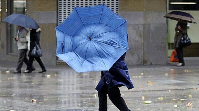 Una mujer camina bajo las lluvias (Imagen de archivo)