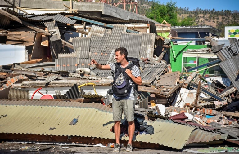 Un turista junto a varias casas destruidas en la isla indonesia de Lombok