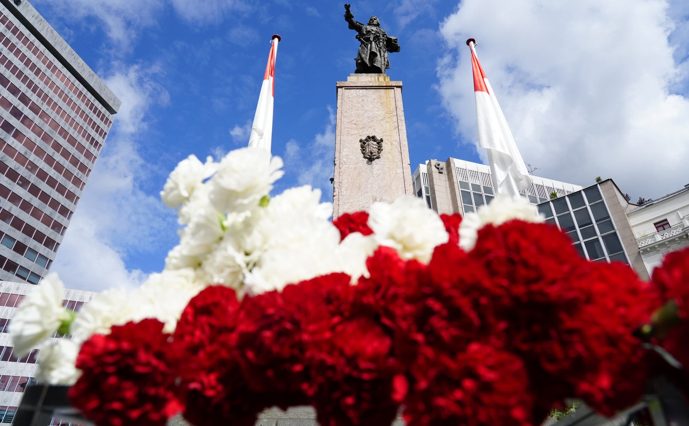 Ofrenda floral ciudadana ante la estatua de Don Diego López de Haro, fundador de la Villa, con claveles rojos y blancos como símbolo de identidad bilbaína.