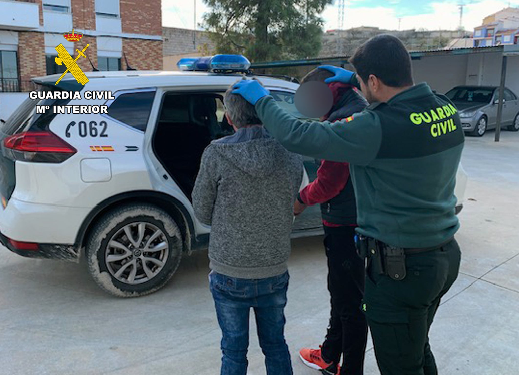 Un agente de la Guardia Civil traslada a dos de los detenidos en la Operación ‘Dylule’