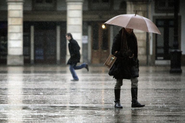 GRA261. A CORUÑA, 15/01/2015.- Varias personas caminan bajo la lluvia por la plaza de María Pita, en A Coruña. Un frente activo asociado a una profunda borrasca situada al norte de Irlanda traerá mañana a Galicia lluvias y vientos intensos, según la predicción de Meteogalicia. EFE/Cabalar