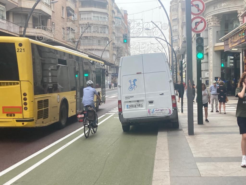 Un ciclista pasa junto a una furgoneta que ocupa parte del carril bici en la Gran Vía de Murcia, mientras un autobús le adelanta por su carril bus