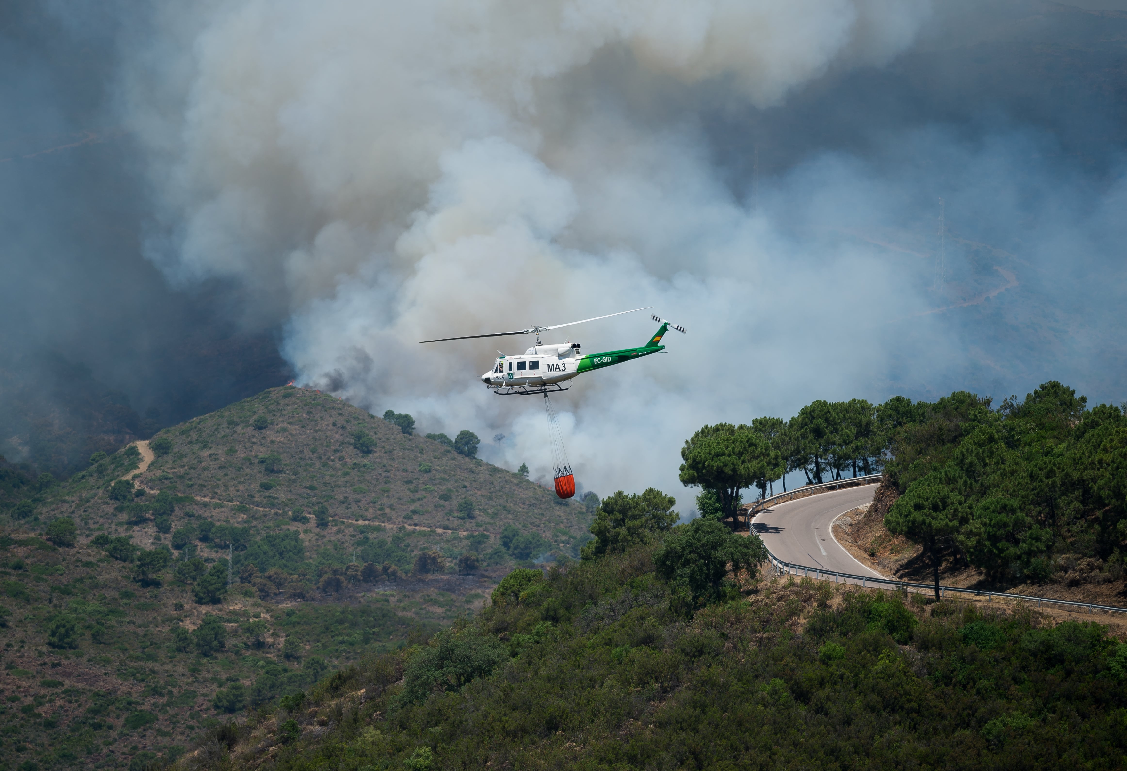 Un helicóptero de bomberos sobrevuela el incendio de Pujerra (Málaga).