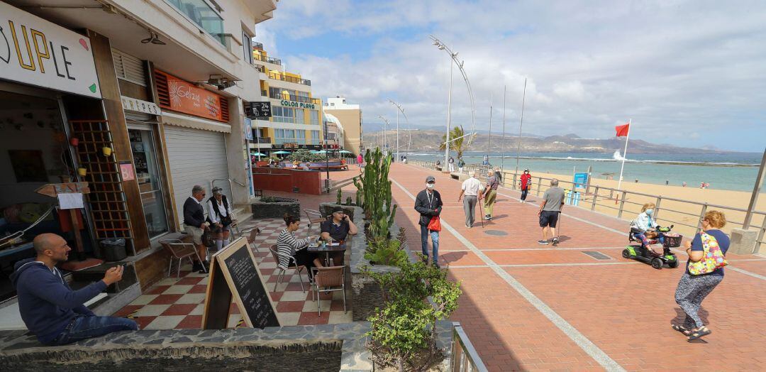  Varias personas disfrutan este lunes de un café en una terraza mientras otras caminan por el paseo de la playa de Las Canteras, en Las Palmas de Gran Canaria, en el primer día de la fase 1 de la desescalada en Canarias. 