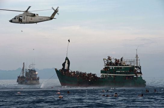 TO GO WITH SEAsia-migrants-boat,FOCUS by Thanaporn PROMYAMYAI, Preeti JHA  (FILES) This file photo taken on May 14, 2015 shows Rohingya migrants swimming to collect food supplies dropped by a Thai army helicopter after they jumped from a boat (R) drifting