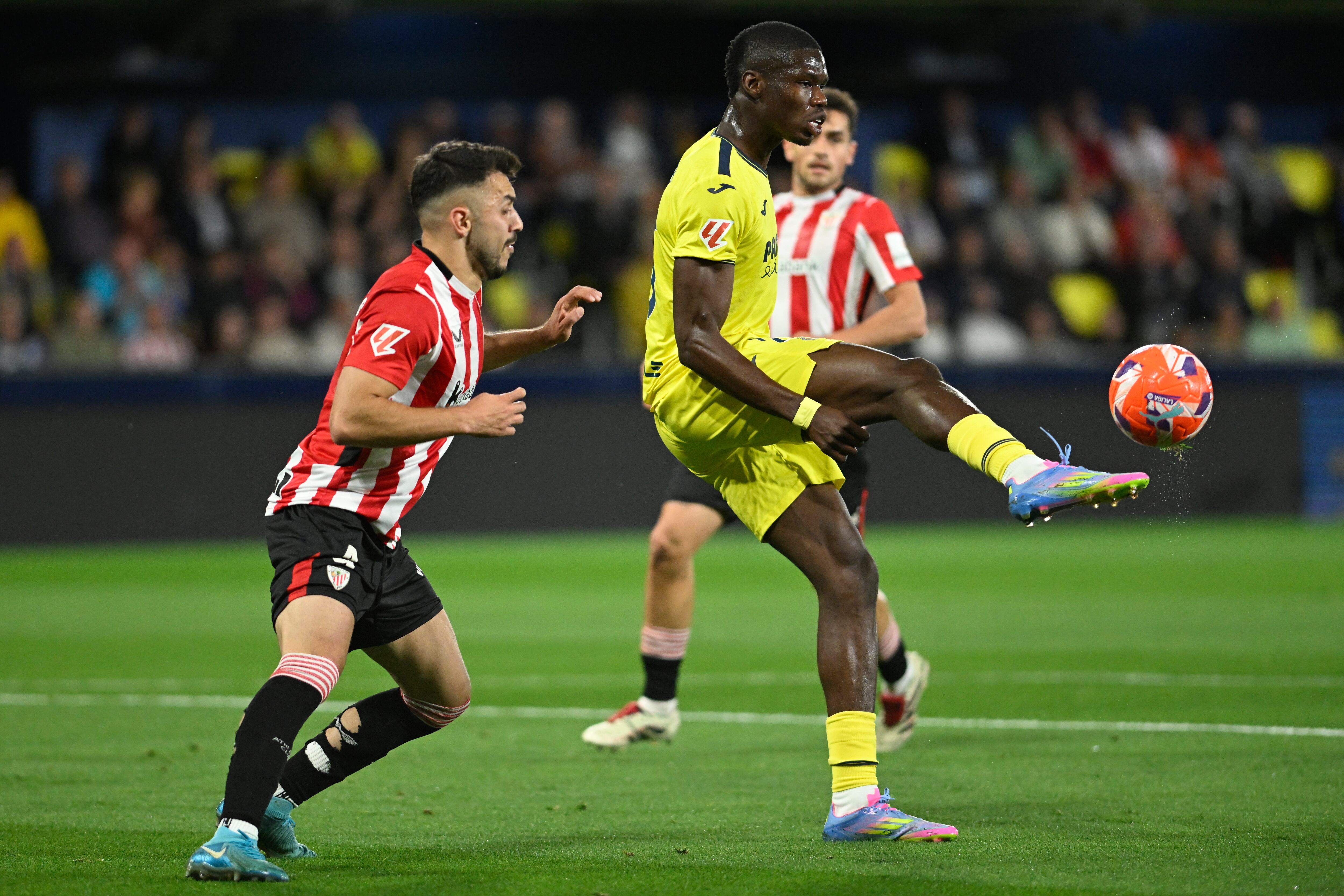 VILLARREAL (CASTELLÓN), 06/04/2025.- El defensa del Athletic Club Aitor Paredes (i) pelea un balón con el delantero francés del Villarreal Thierno Barry durante el encuentro correspondiente a la jornada 30 de Laliga EA Sports que disputan hoy domingo Villarreal y Athletic Club en el estadio de La Cerámica, en la localidad castellonense. EFE / Andreu Esteban.