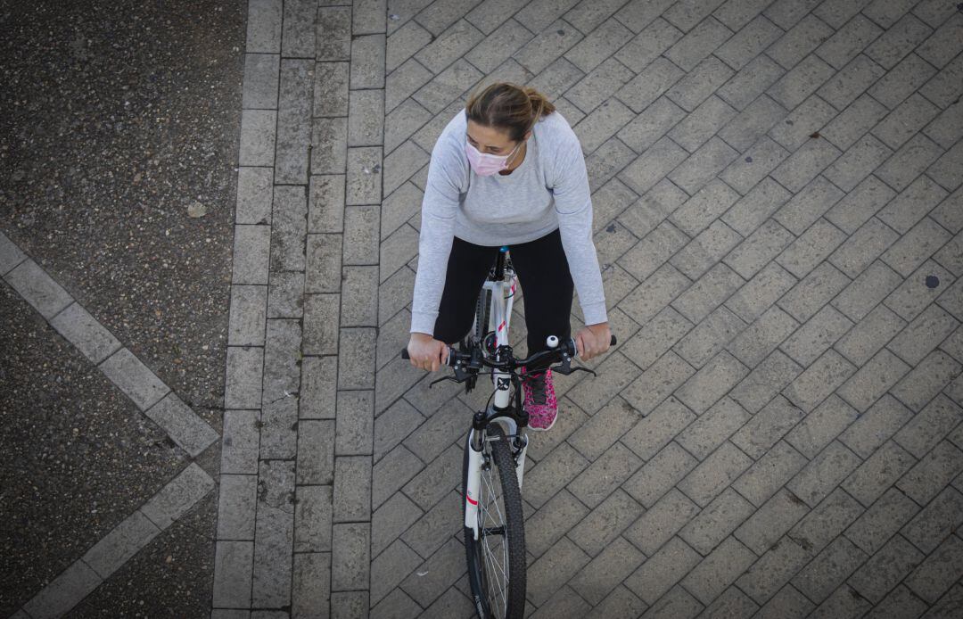 Una mujer, en bicicleta portando la mascarilla.