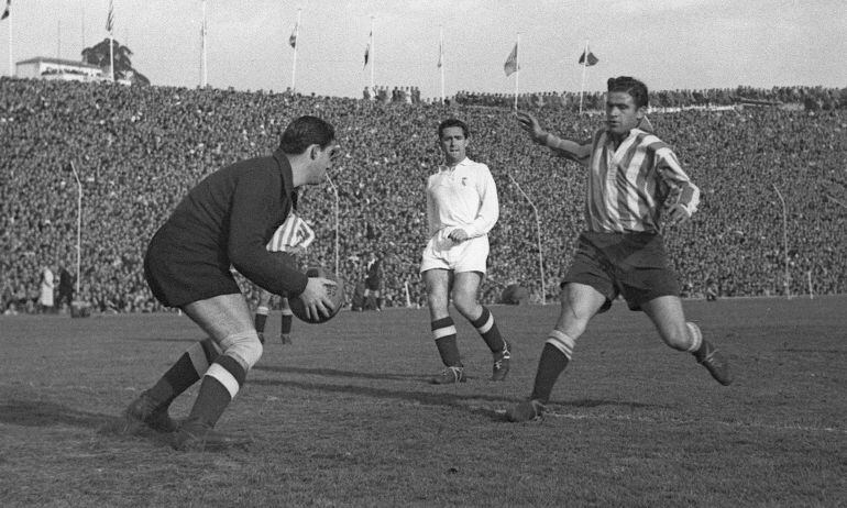 El jugador del Atlético de Madrid Farías intenta llegar a un balón que coge en sus manos el meta del Real Madrid Bañón, durante un partido de Liga disputado en el estadio Metropolitano en 1949.