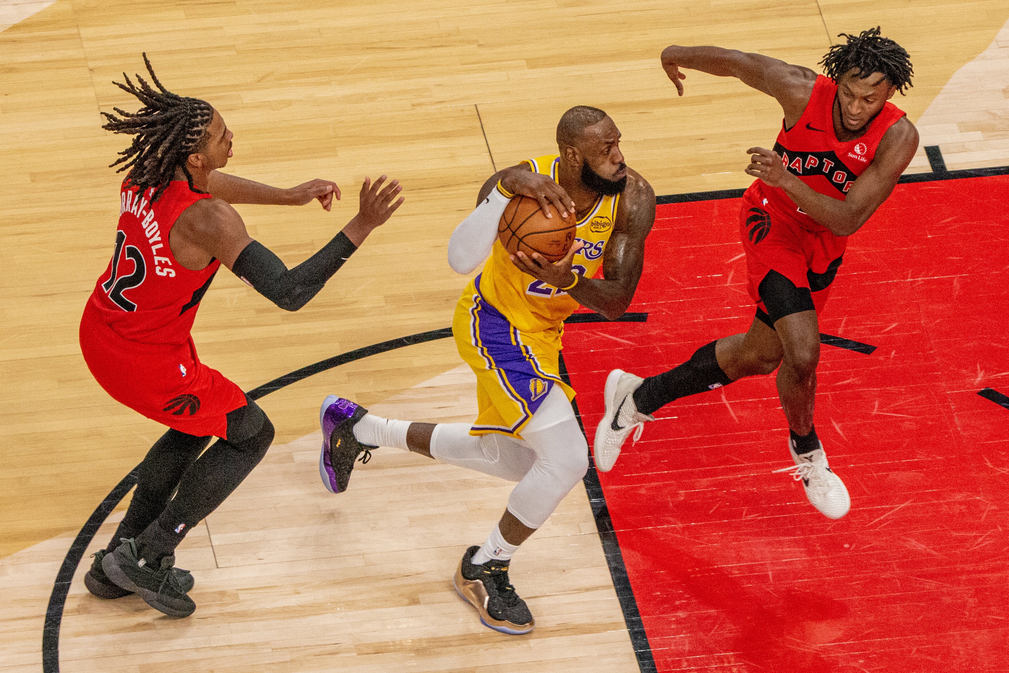 LeBron James intenta zafarse de Collin Murray-Boyles en el duelo entre Toronto Raptors y Los Angeles Lakers