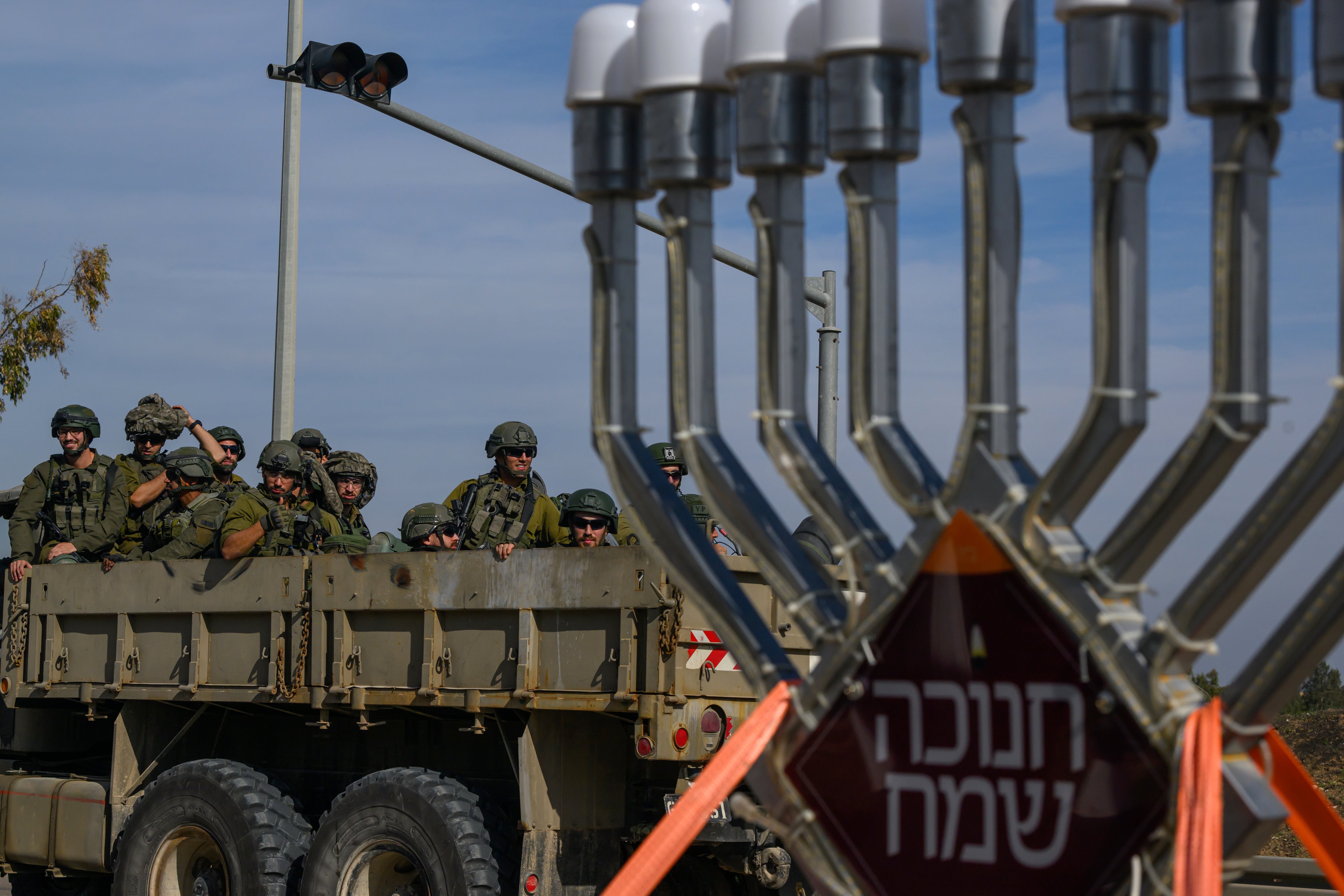 Soldados israelíes en un camión pasan junto a una menorá