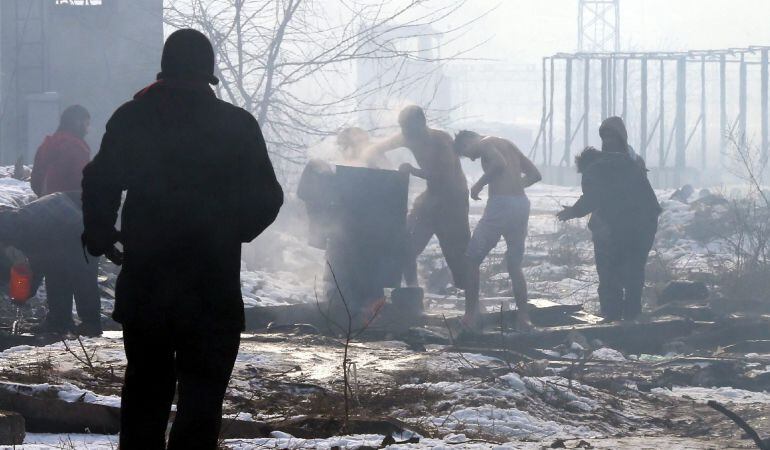 Varios refugiados hierven un bidón de agua para lavarse en un asentamiento en Belgrado, Serbia.