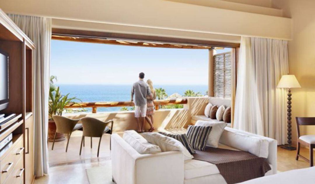 Una pareja observa el mar en la habitación de un hotel