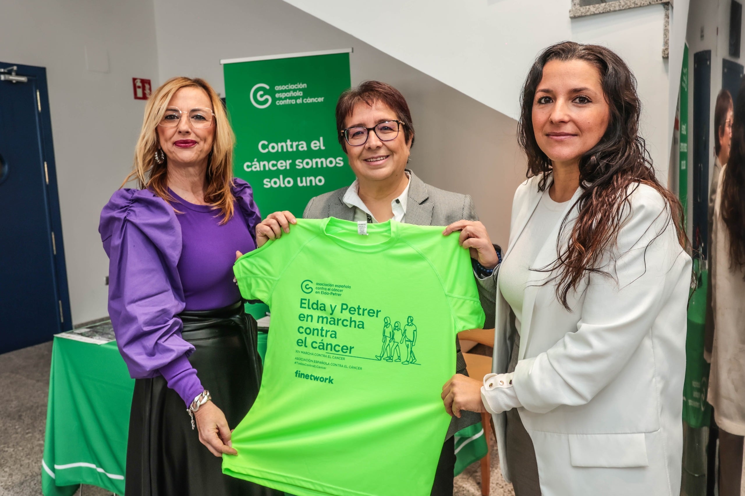 Juani Ochoa, concejala de Participación Ciudadana de Petrer; Ana Juan, presidenta de la AECC Elda - Petrer y Elisabeth Belda, concejala de Salud de Elda; han presentado la camiseta para la Marcha Solidaria