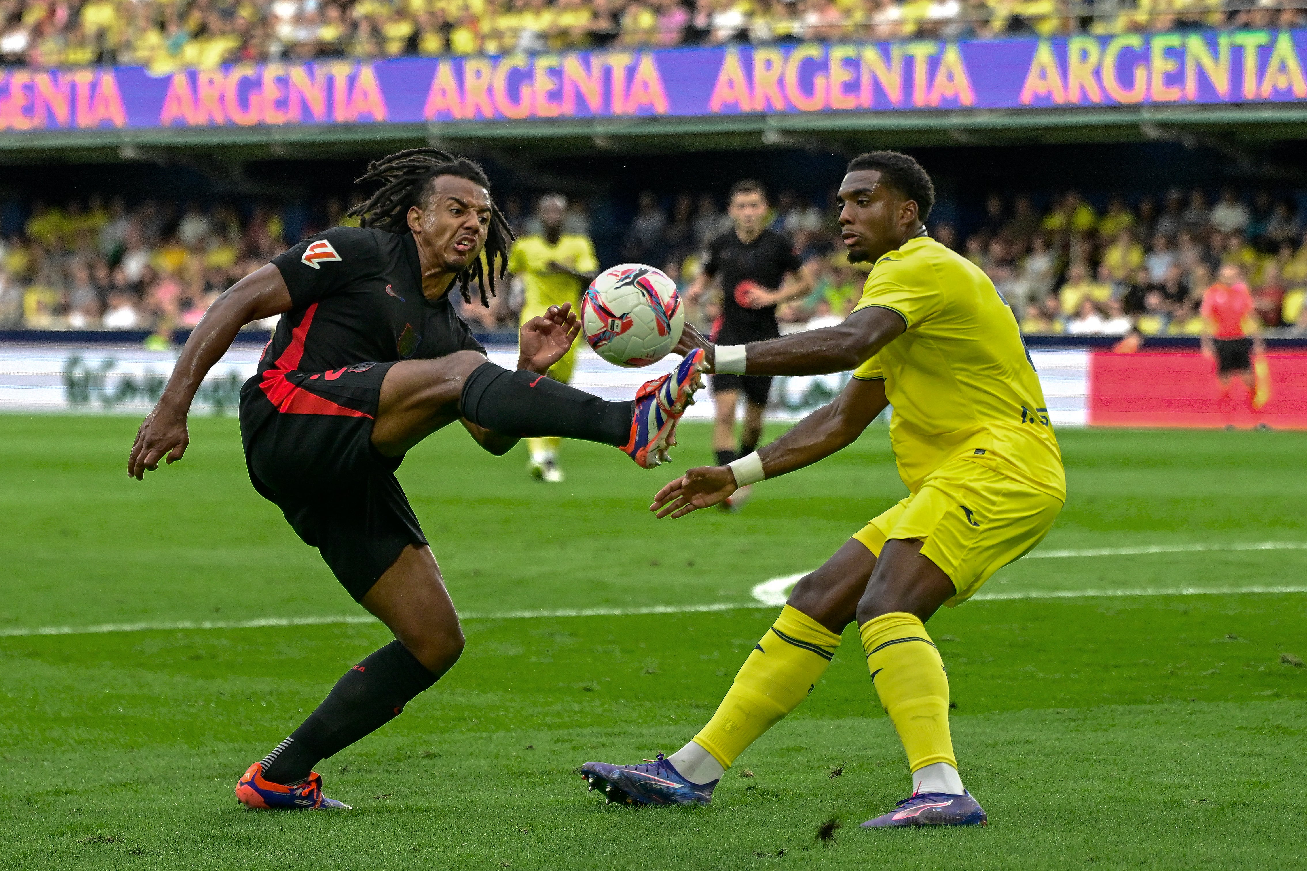 VILLARREAL, 22/09/2024.- El defensa francés del FC Barcelona, Jules Koundé (i), disputa el balón ante el defensa caboverdiano del Villarreal, Logan Costa, durante el encuentro correspondiente a la sexta jornada de Laliga EA Sports que disputan hoy Domingo FC Barcelona y Villarreal en el estadio de La Cerámica, en la localidad castellonense. EFE / Andreu Esteba.
