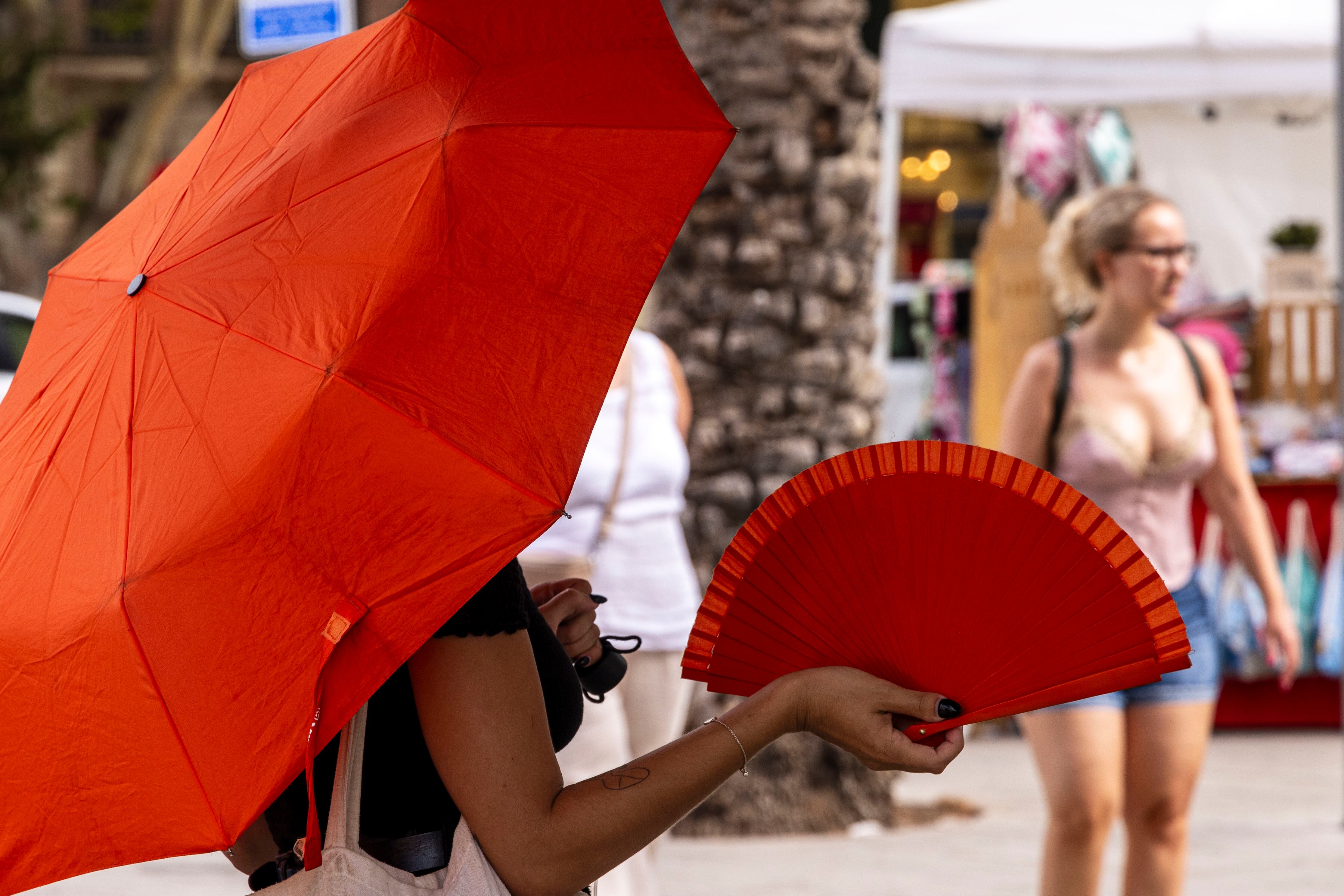 PALMA, 24/07/2023.- Siguen las altas temperaturas en Mallorca. Una mujer combate doblemente el calor esta mañana en el Parc de la Mar de Palma. EFE/CATI CLADERA
