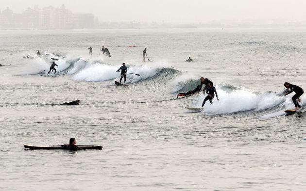 Decenas de surfistas practican, durante la franja horaria permitida, en la playa de la Malvarrosa, en Valencia, hoy quincuagésimo sexto día del estado de alarma