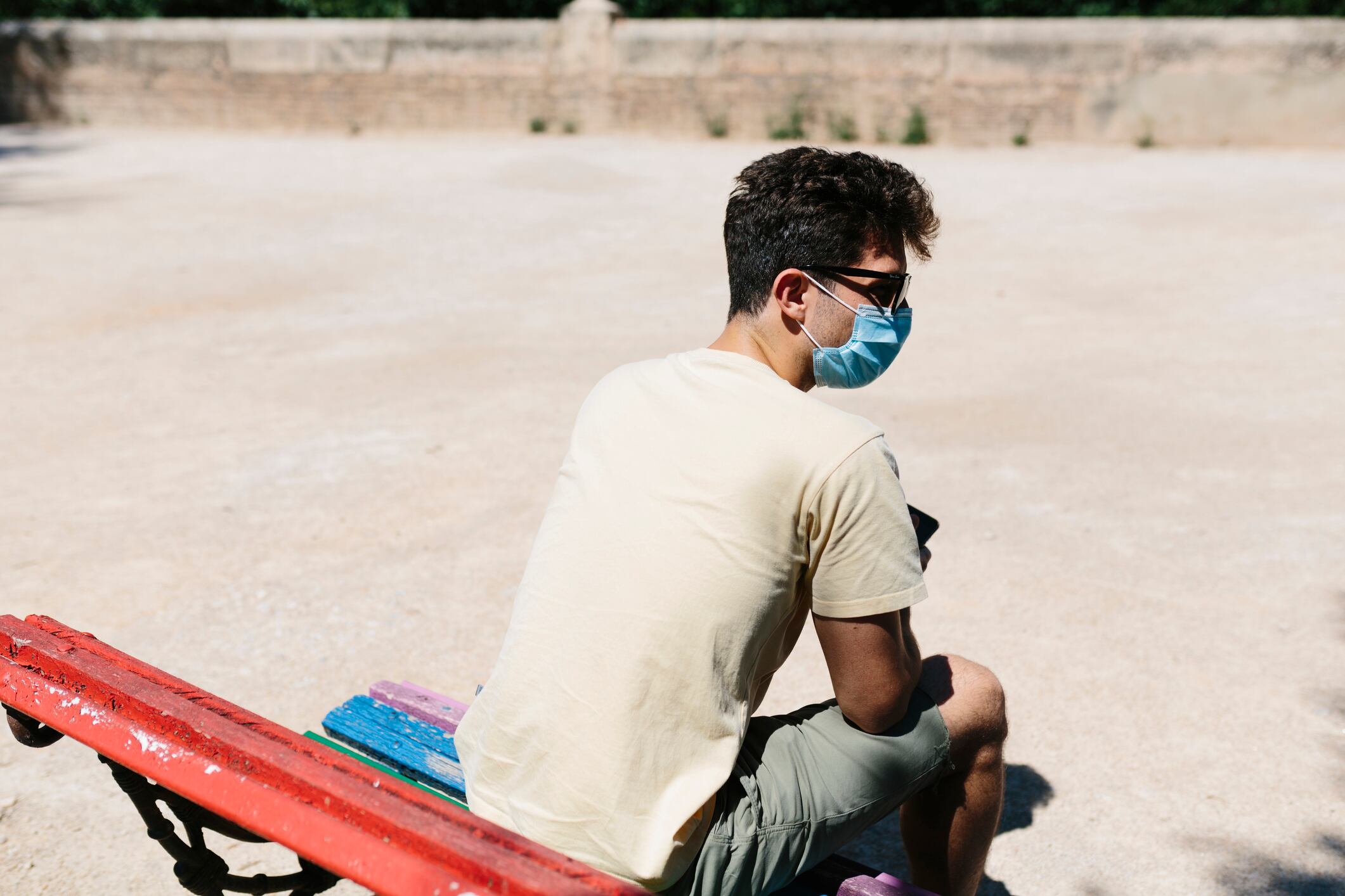 Joven usando la mascarilla en un banco. - Archivo.