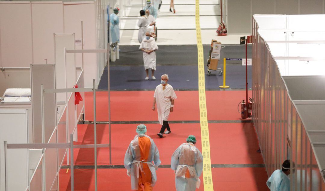 Trabajadores sanitarios protegidos caminan por el interior del hospital de campaña montado en IFEMA.