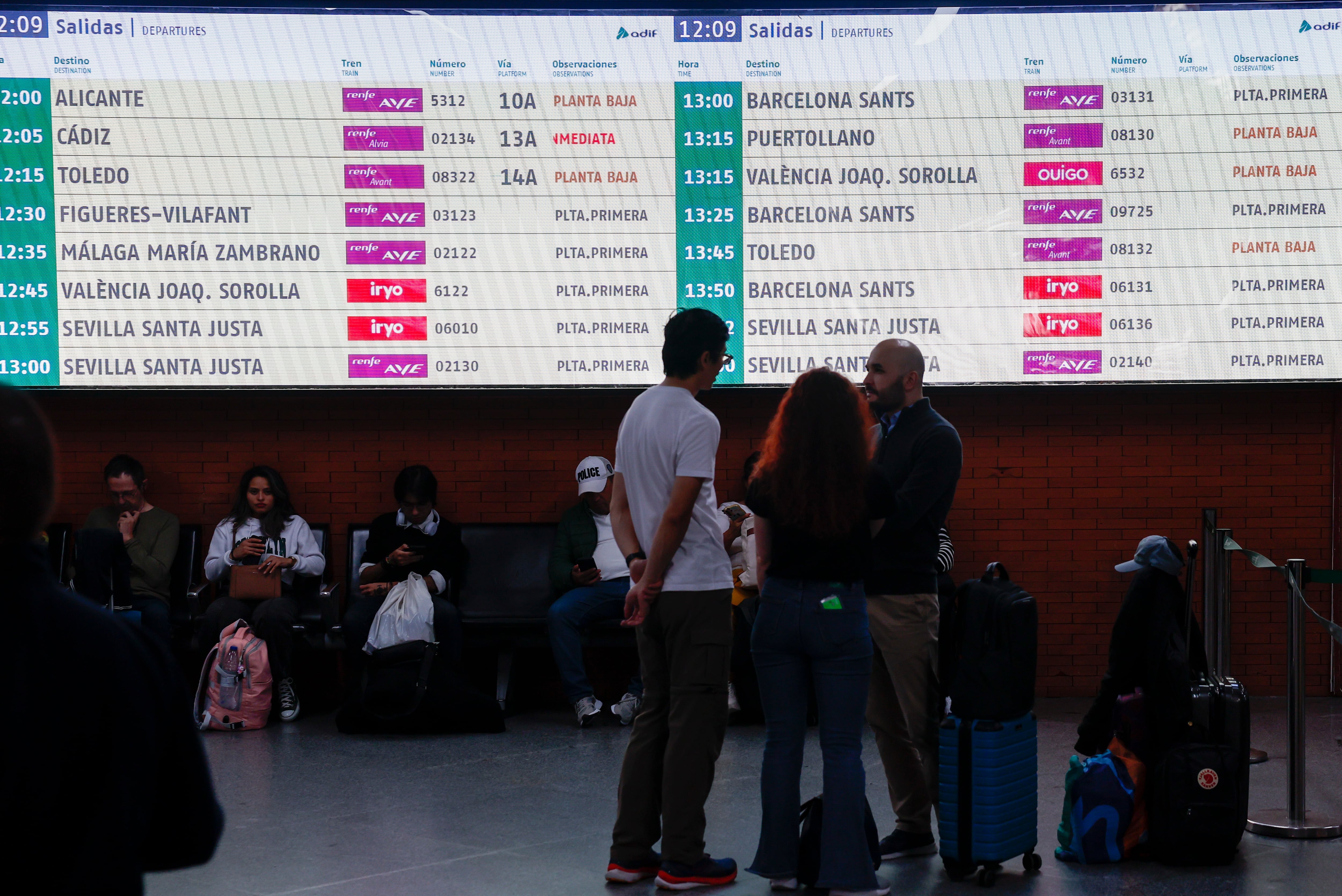 Varias personas esperan la salida de su tren en la estación de Atocha en Madrid.