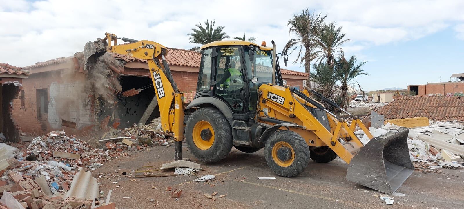 Una excavadora trabajando en el derrumbe de las estructuras que aún quedan en pie dentro de la parcela