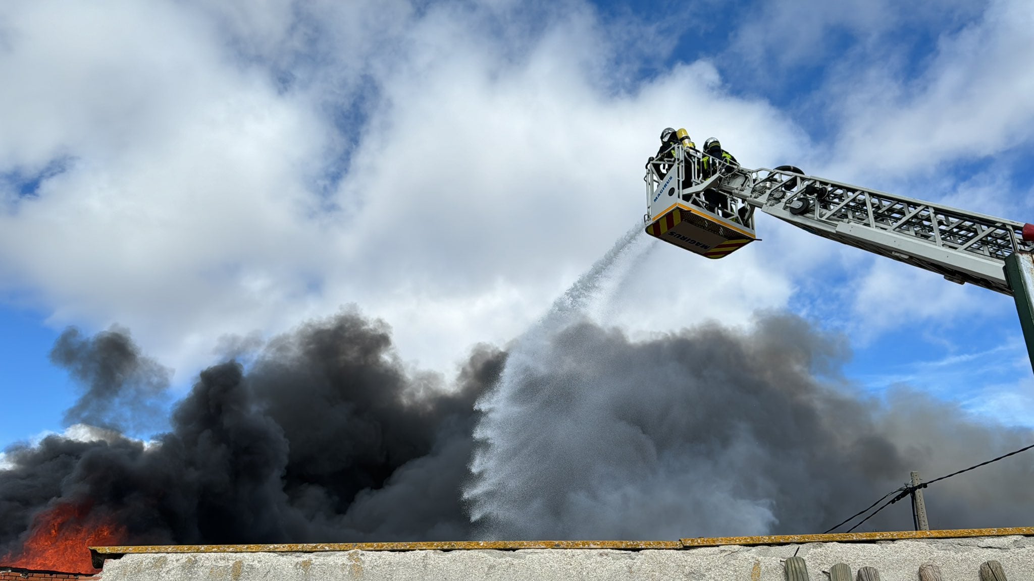 Los bomberos actuando sobre la columna horizontal de humo