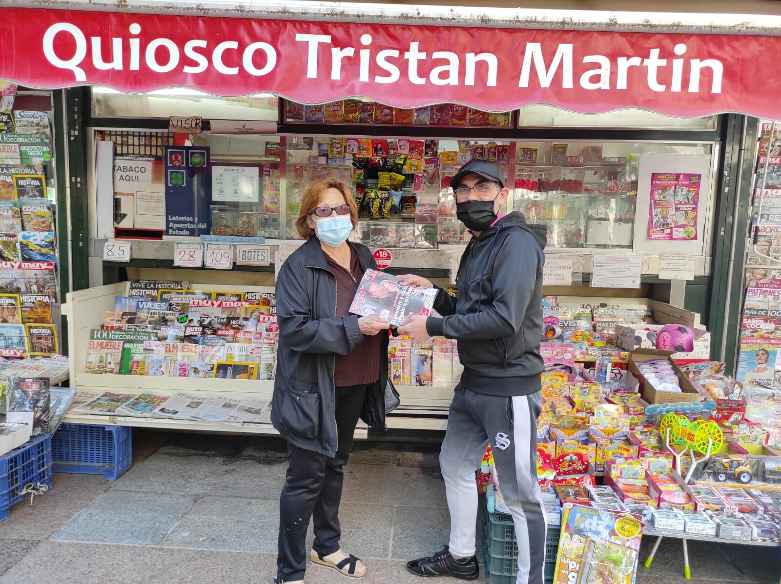 Javi entrega una revista a una clienta habitual en su kiosko