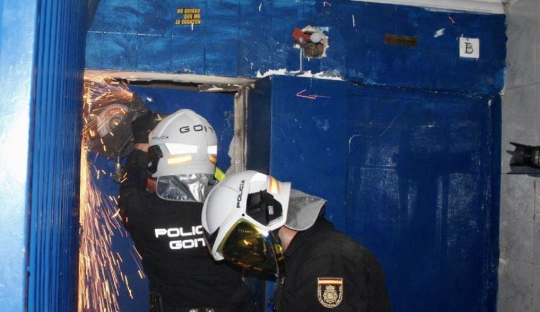 Agentes de la Policía Nacional intentando cortar la puerta blindada